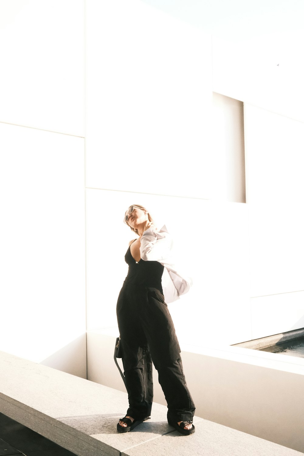 a woman in overalls standing on a ledge