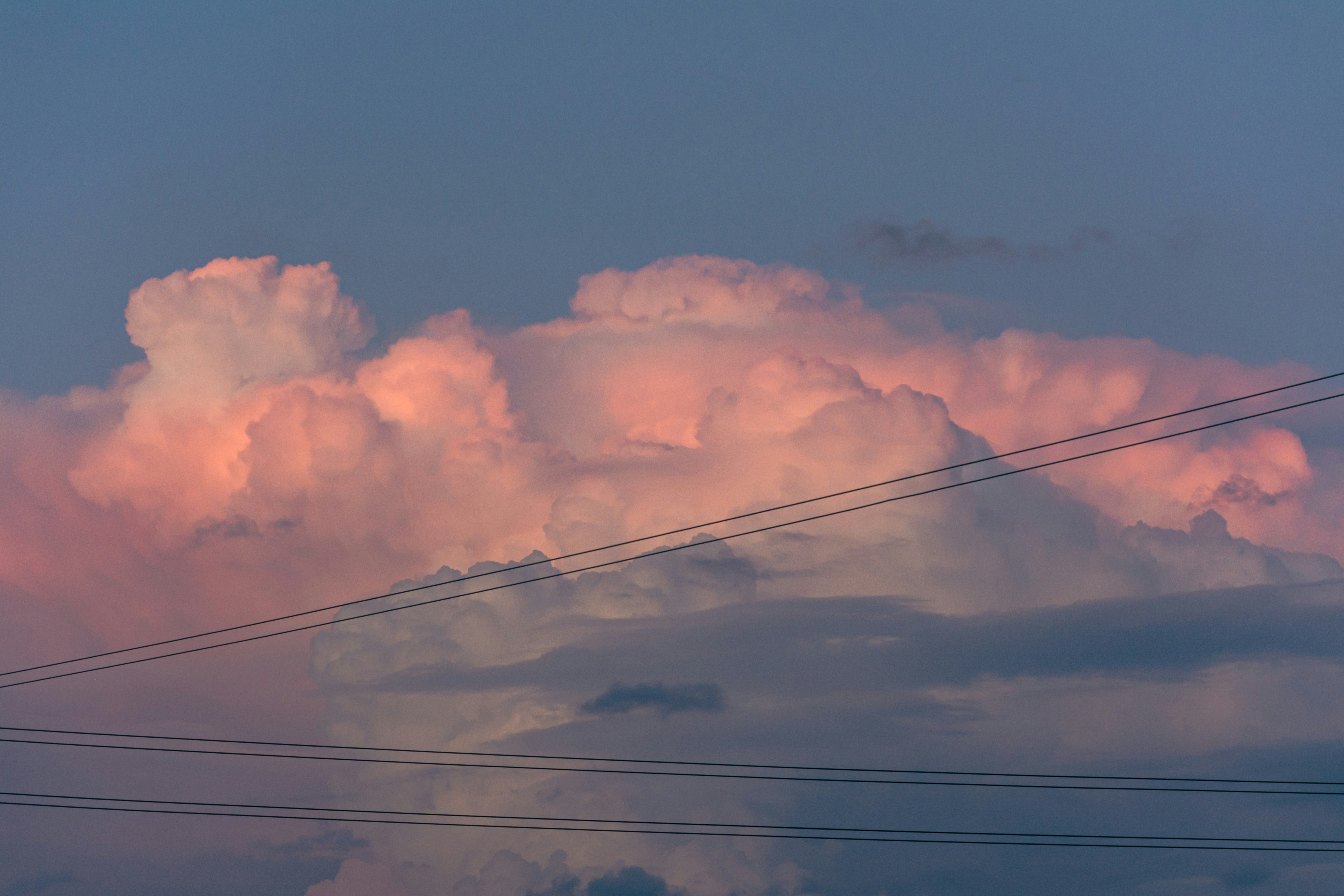 Uma grande nuvem está no céu acima das linhas de energia