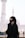 a woman in a black hijab is standing in front of a white building