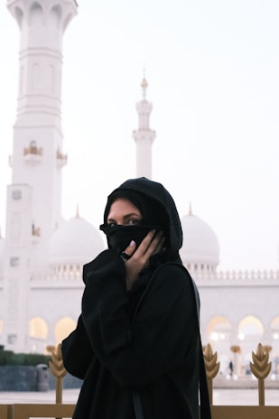 a woman in a black hijab is standing in front of a white building