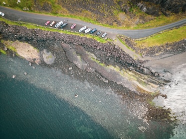 Aerial view of a coastal gas station with cars fueling and the sea stretching beyond.