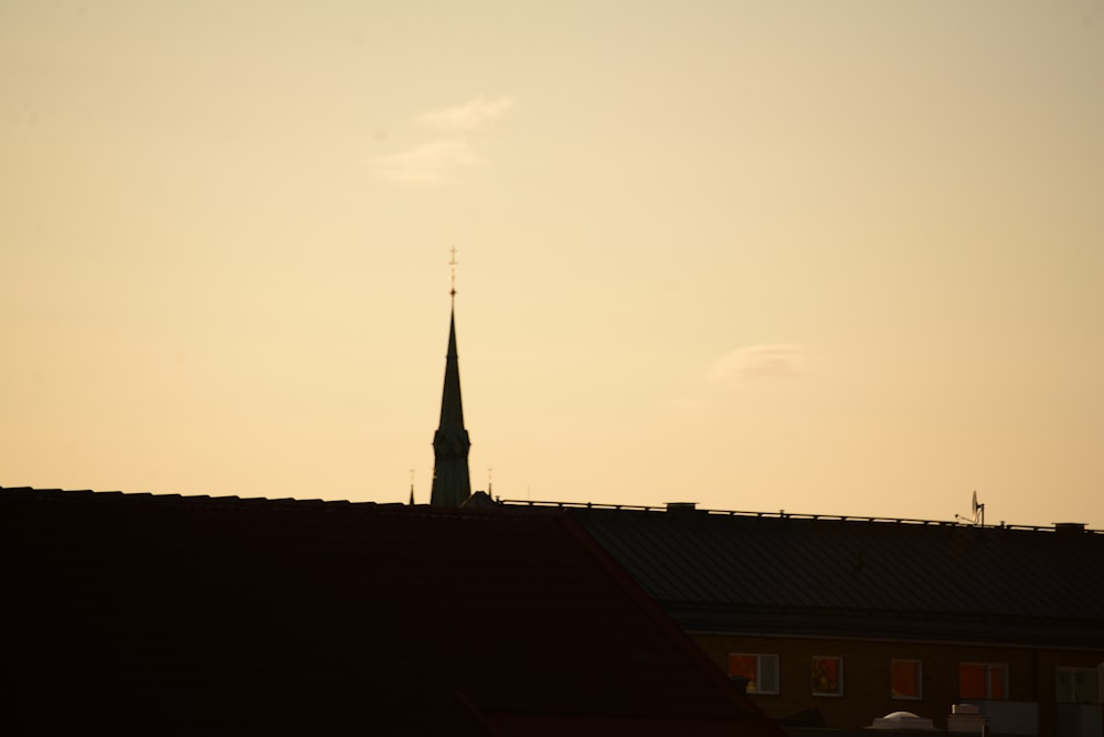 a church steeple is silhouetted against a sunset sky