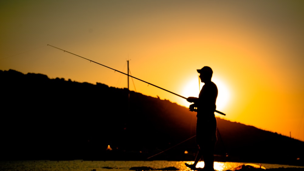 a man standing on a beach holding a fishing pole