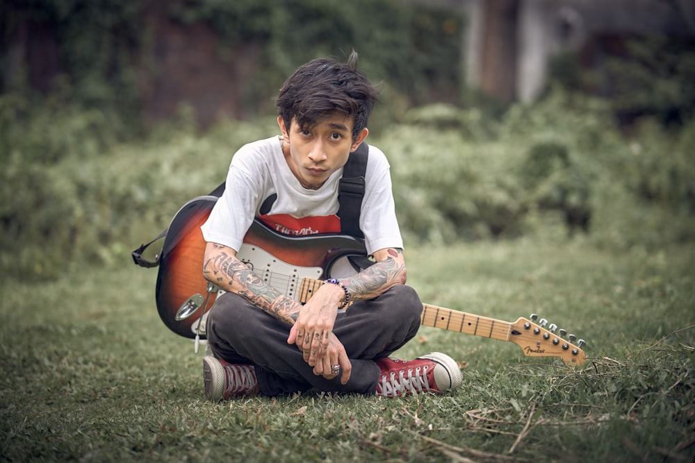 Un jeune homme assis par terre avec une guitare