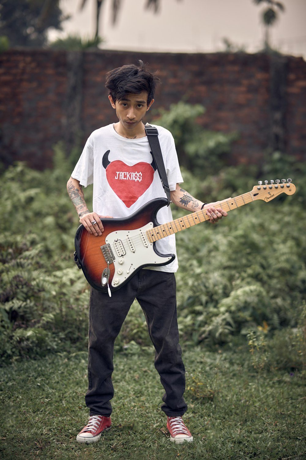 a young man holding a guitar with a heart on it