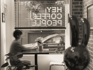 A friendly notary public meeting a client at a cozy coffee shop in Albuquerque, with desert landscape visible through the window.
