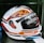 A detailed view of a motorcycle helmet with a glossy design that includes bold text and geometric patterns. The helmet features words like 'TROOPER' and 'SCRATCH RESISTANT' across the surface, with technical details and a visible visor mechanism.