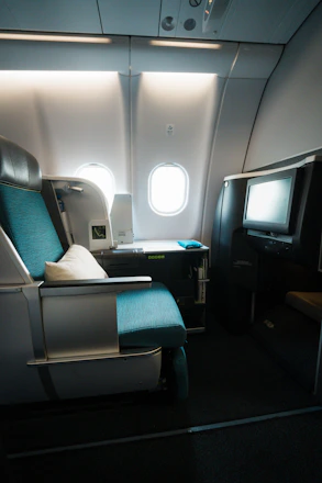 Luxurious business class airplane seat bathed in soft teal and gold lighting.