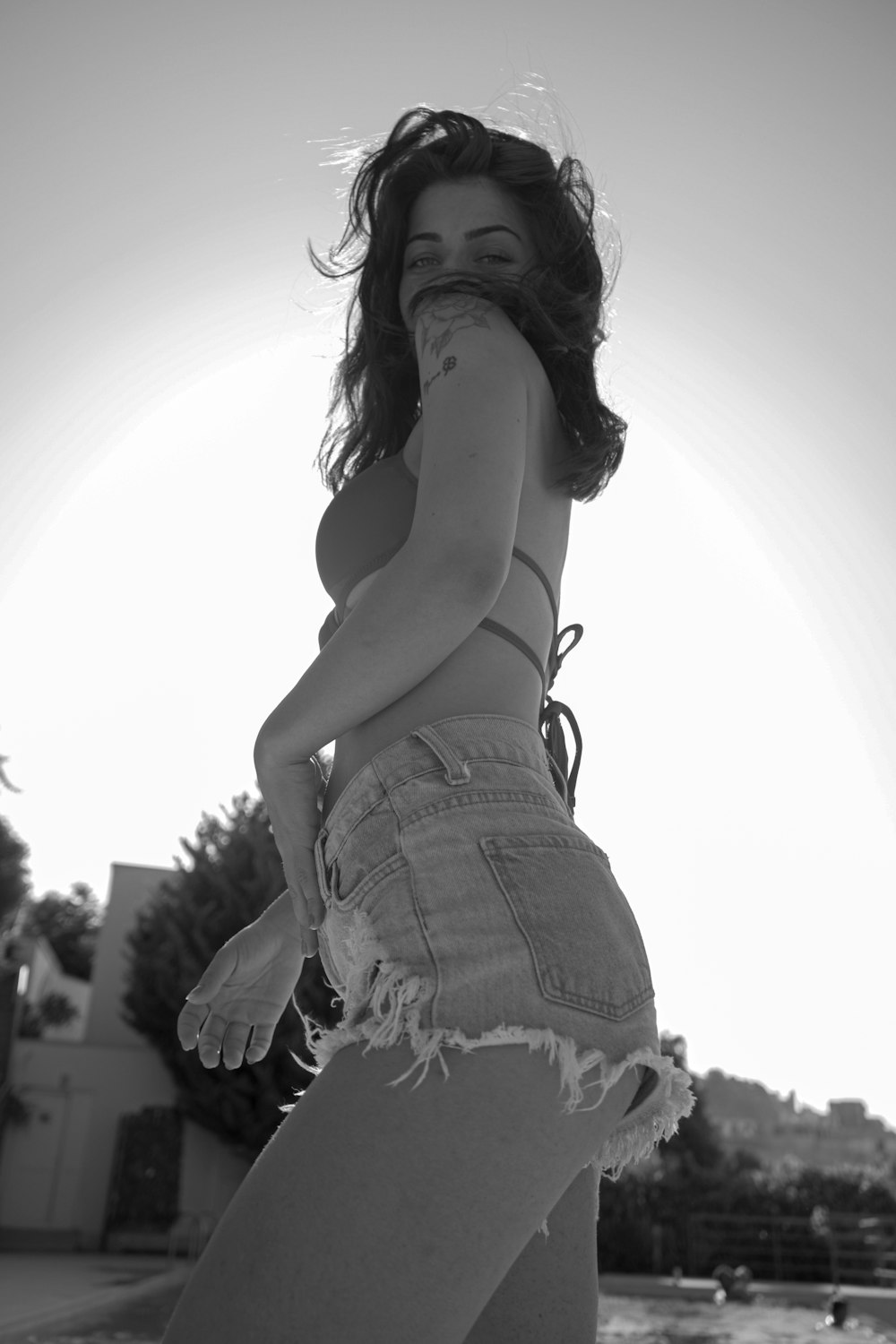 a woman in high waisted shorts standing in front of a body of water