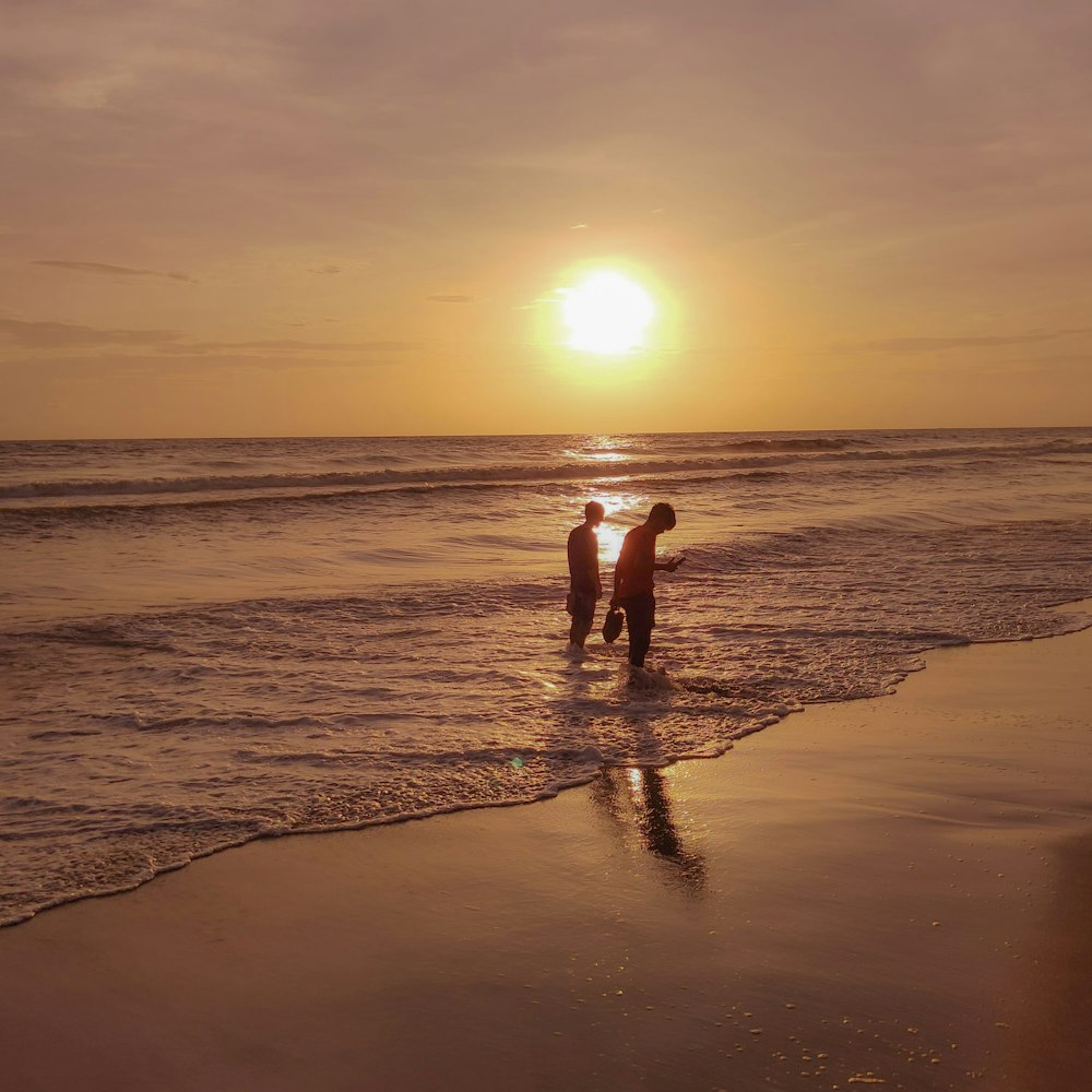 a couple of people standing in the water at the beach