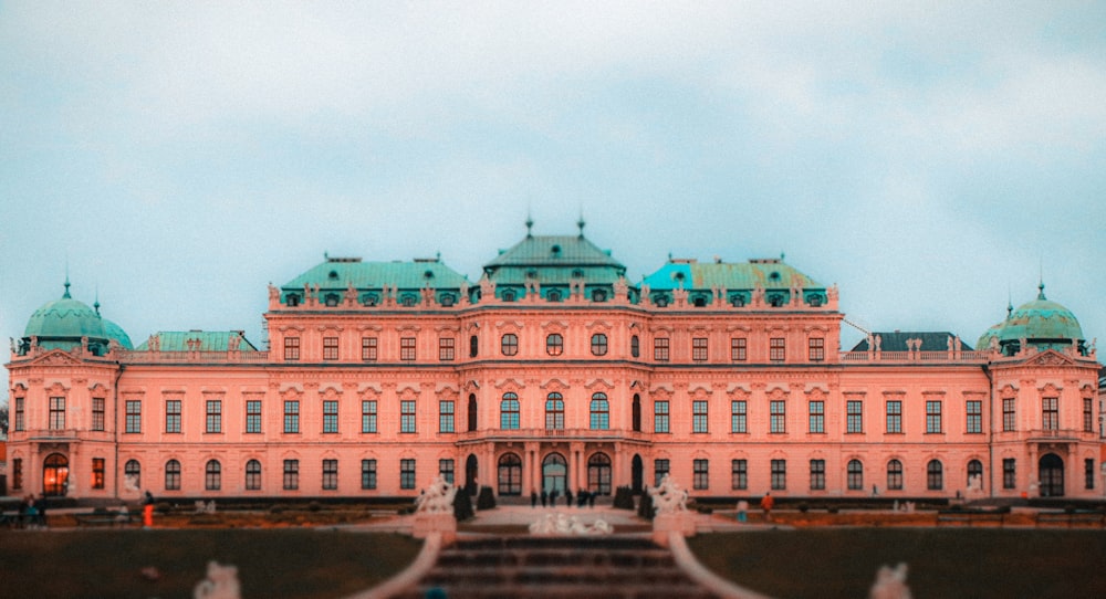 a large pink building with a green roof