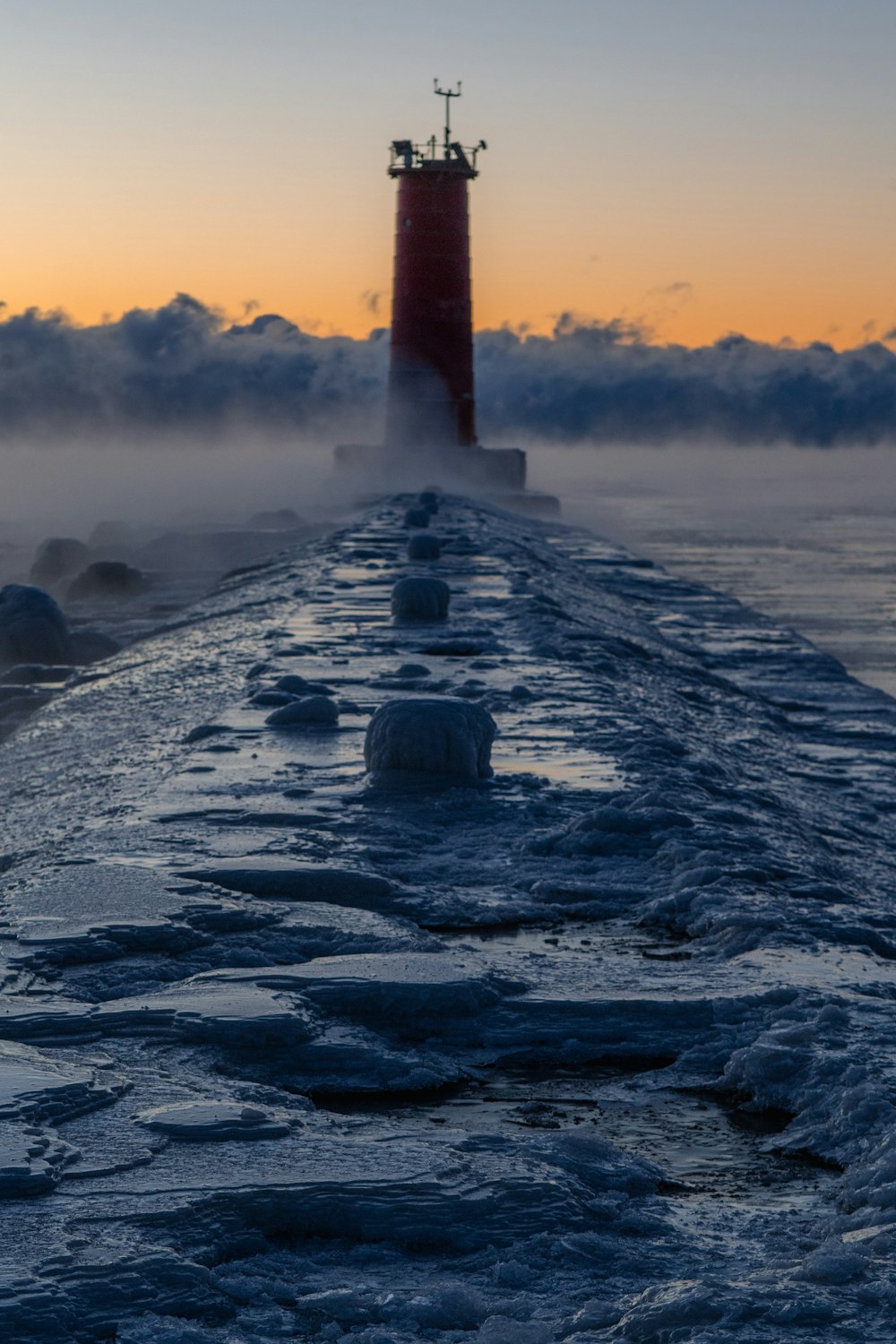 a red light house sitting on top of a pier