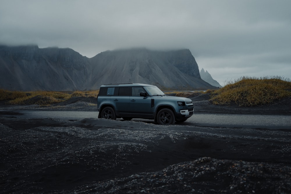 a blue land rover parked in front of a mountain