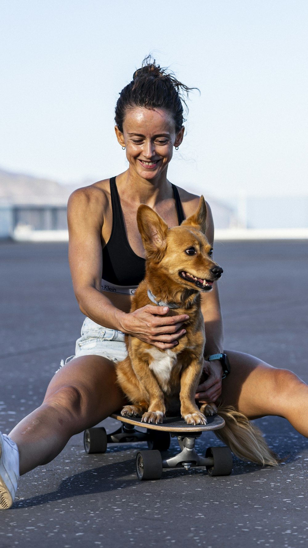 a woman sitting on a skateboard holding a dog