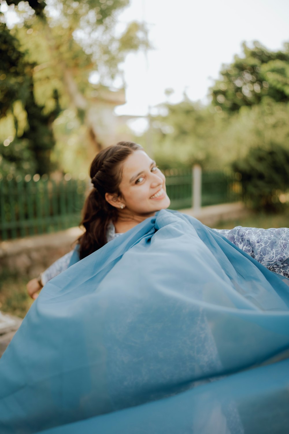 a woman wrapped in a blue blanket in a park