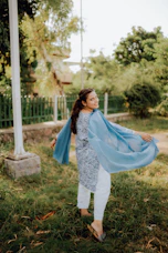 A joyful woman twirling in a flowing designer kurti, the fabric catching light in shades of deep green and gold.