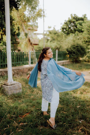 Happy young woman twirling in a flowing embroidered co-ord set with subtle beige and blush hues.