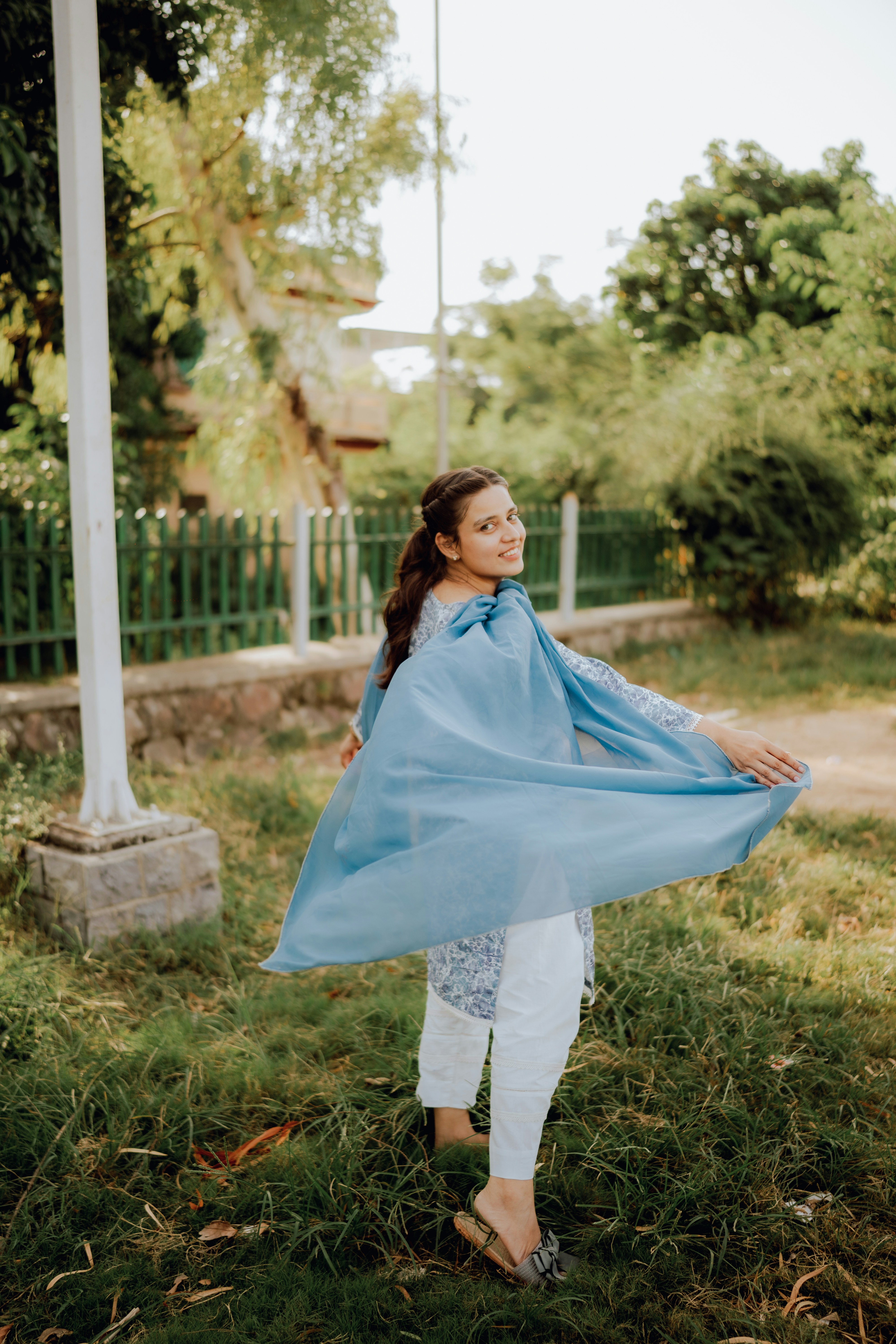 a woman standing in the grass holding a blue blanket
