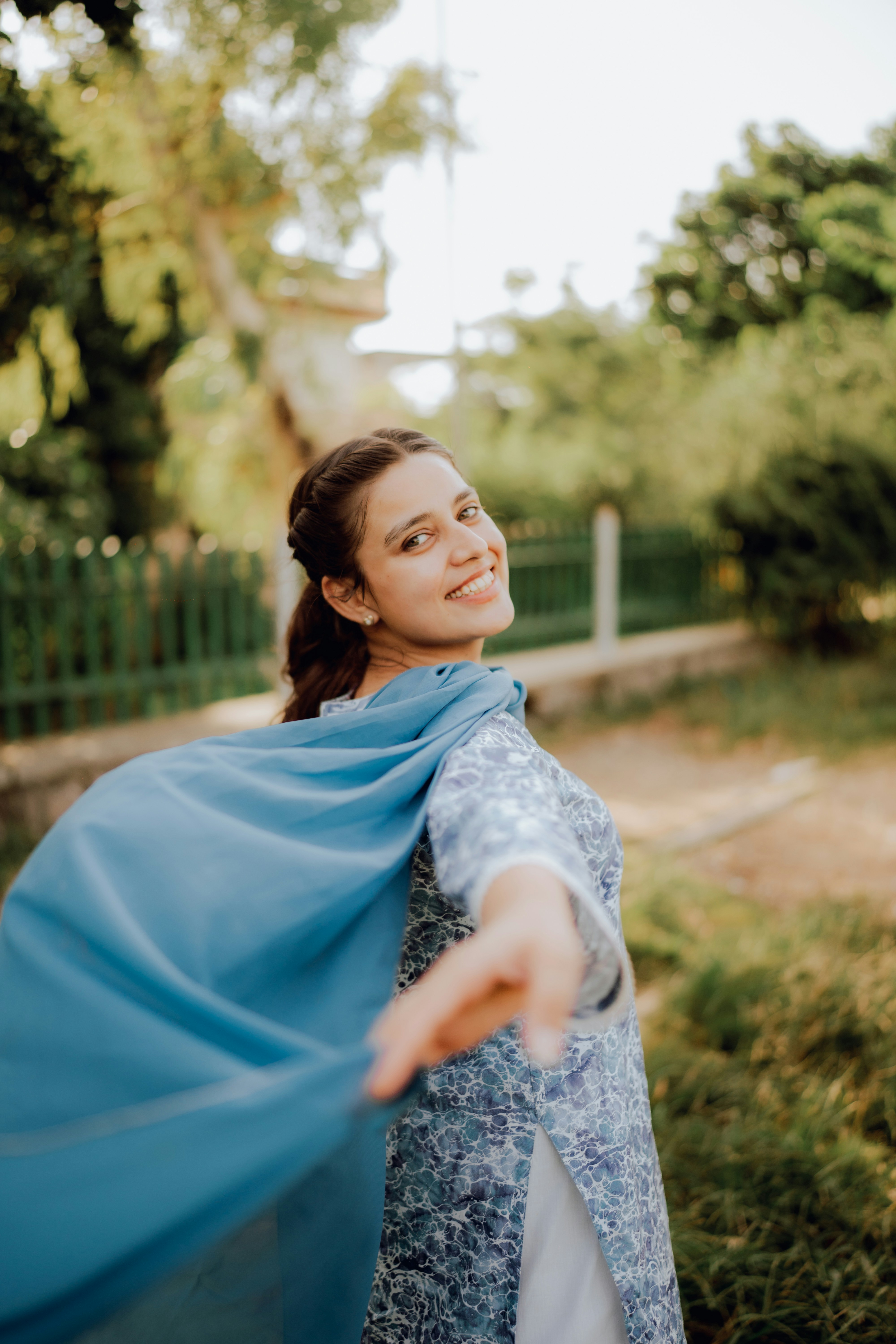 a woman wearing a blue shawl in a park
