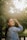 a woman standing in front of a green tree