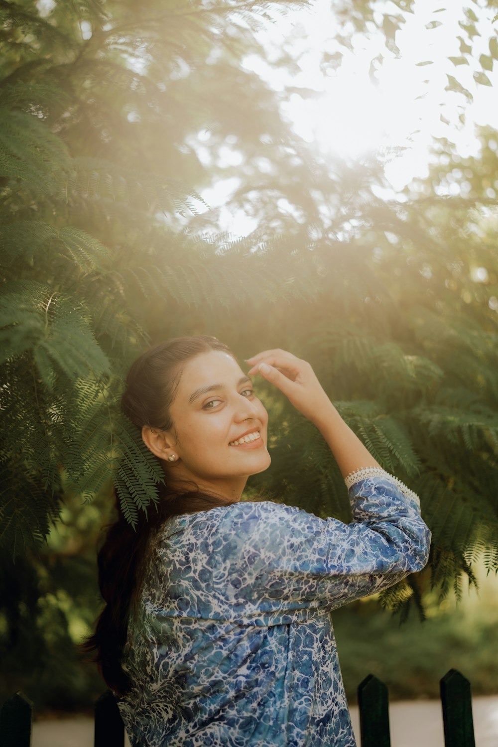 a woman standing in front of a green tree