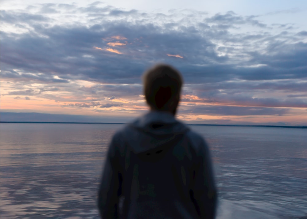 Ein Mann, der auf einem Boot steht und den Sonnenuntergang beobachtet