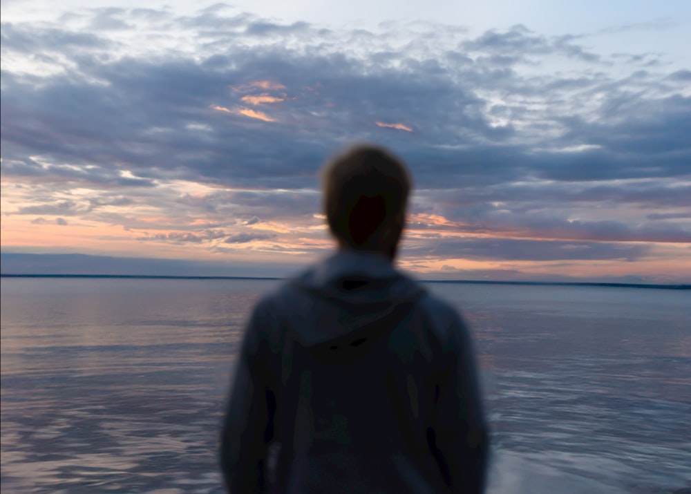 a man standing on a boat watching the sunset