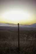 A wide view of a farm and ranch fence stretching across open land.