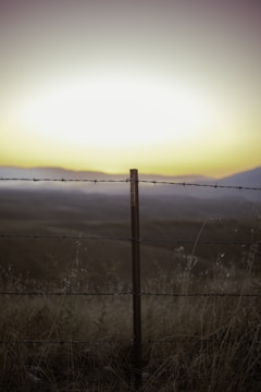 A wide view of a farm and ranch fence stretching across open land.