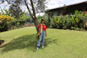 A smiling customer standing in a freshly landscaped garden with lush green grass and vibrant flowers.