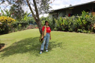 A smiling customer standing in a freshly landscaped garden with lush green grass and vibrant flowers.