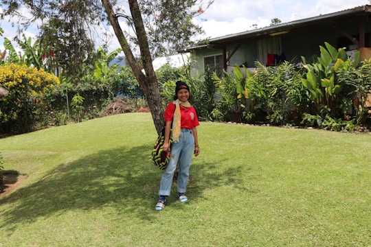 A smiling homeowner standing beside a lush, well-manicured lawn with trimmed shrubs and a stone pathway.