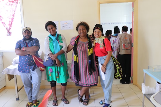 A group of Mexican men and women with light and medium skin tones, dressed casually in official Promotor Autorizado Infinitum uniforms, interacting happily in a bright, open office space.