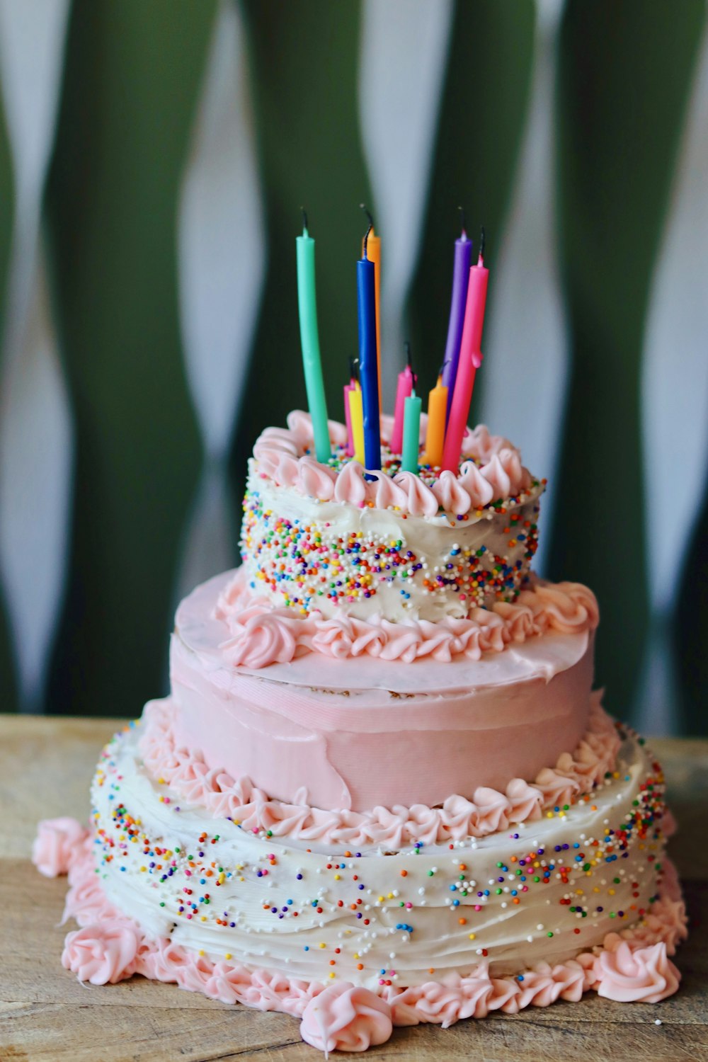 Un pastel de tres niveles con velas que sobresalen de él