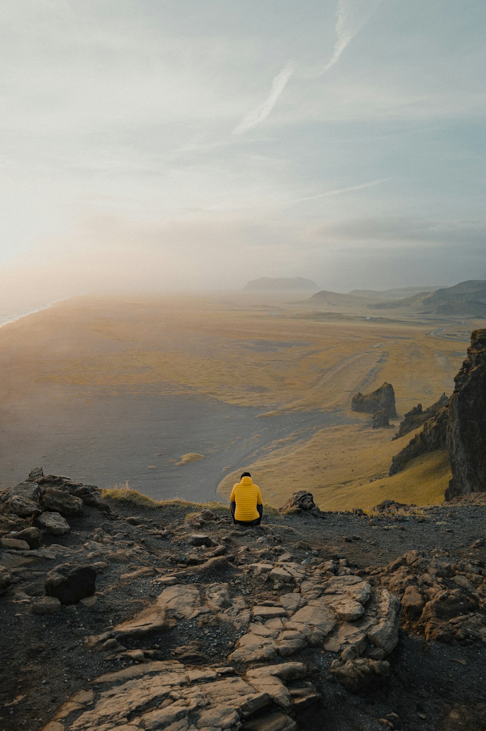 une personne assise au sommet d’une colline rocheuse