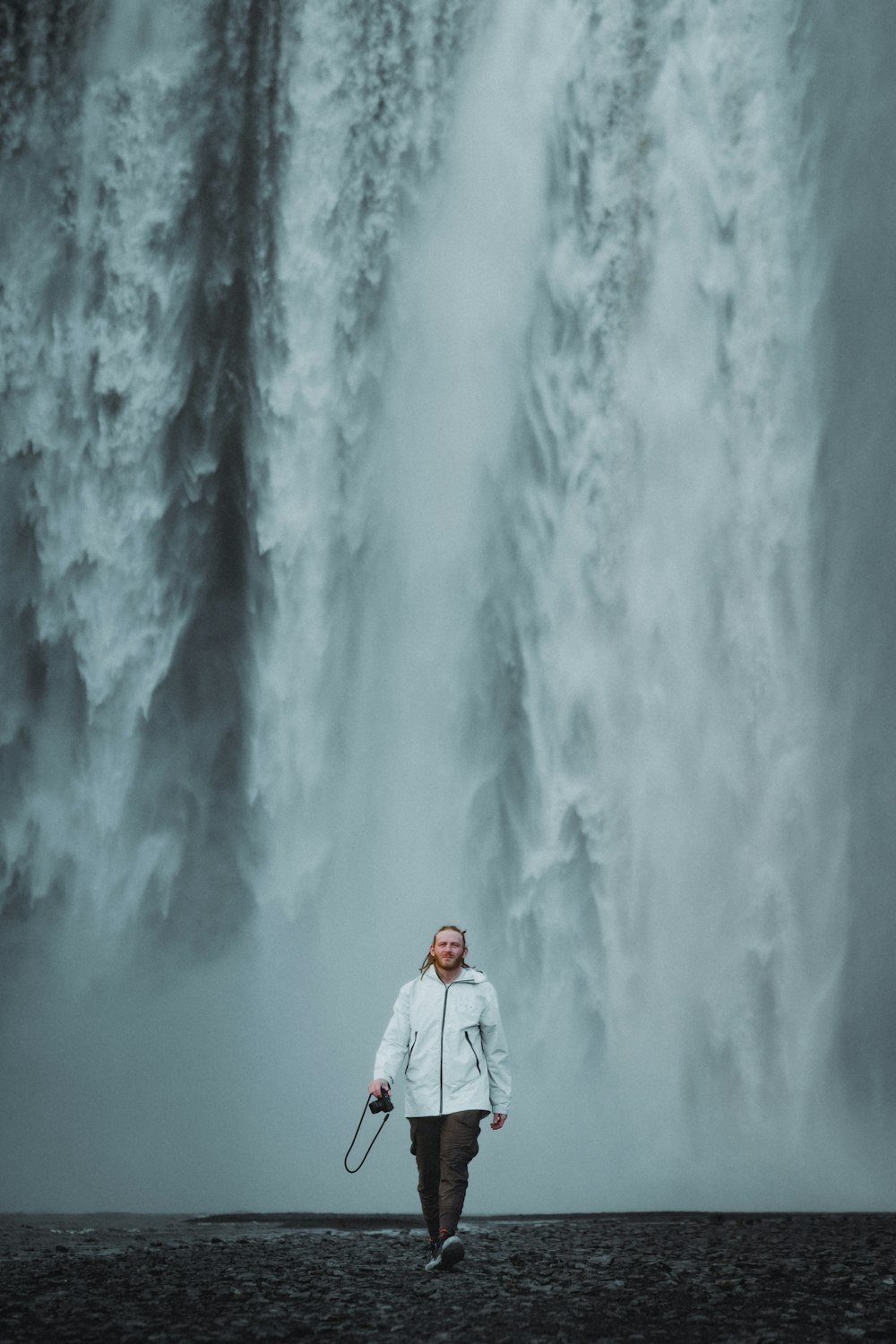 Une femme debout devant une grande cascade