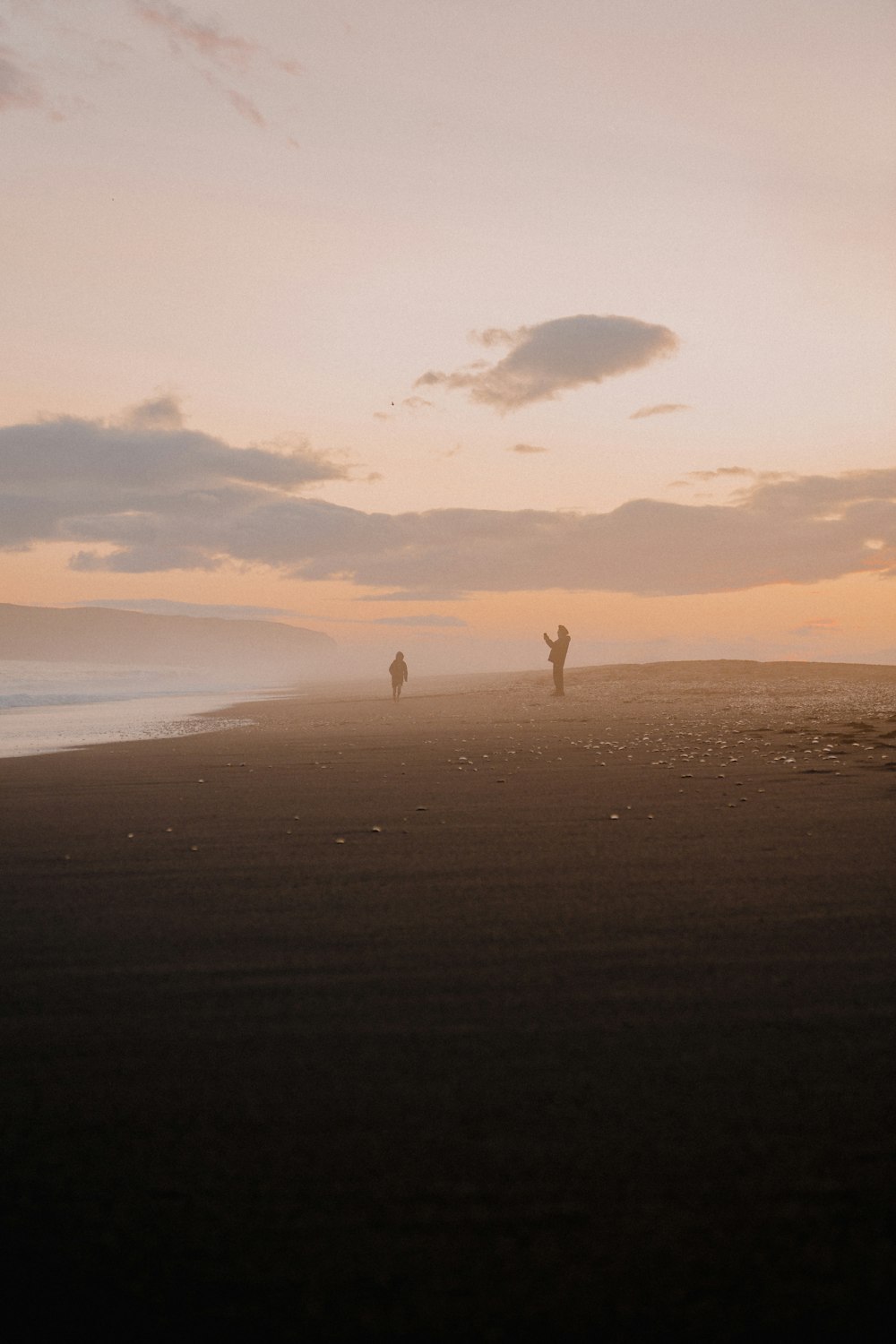 Un paio di persone in piedi sulla cima di una spiaggia sabbiosa