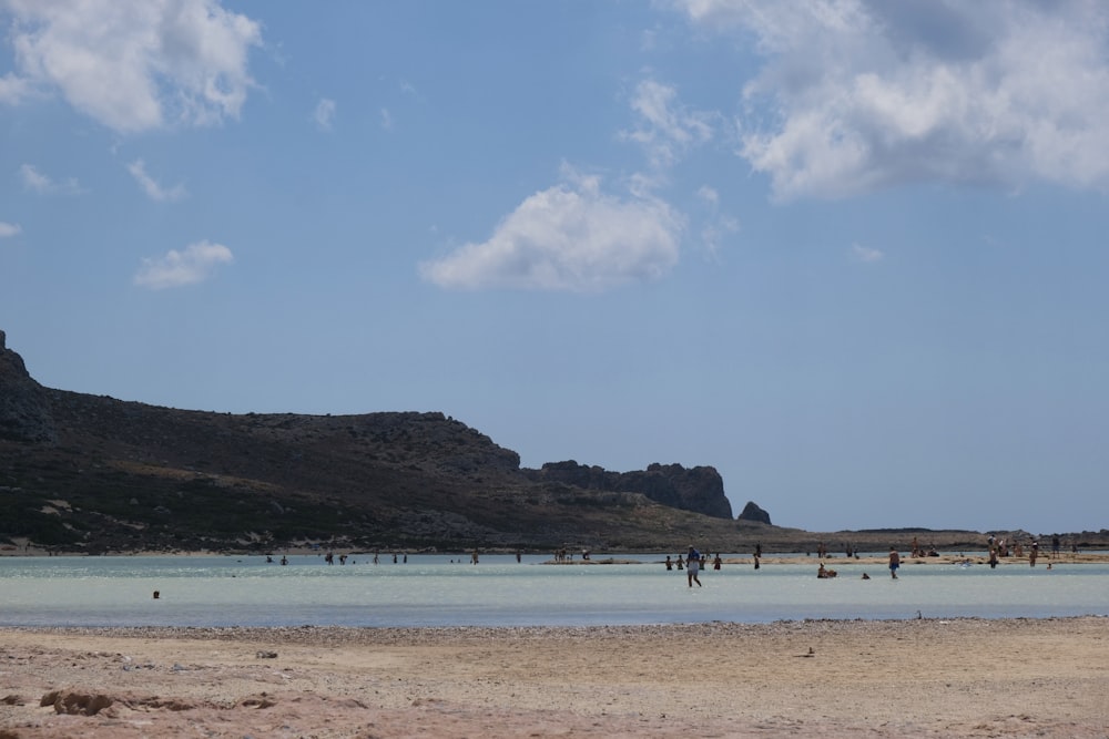 um grupo de pessoas em pé em cima de uma praia de areia