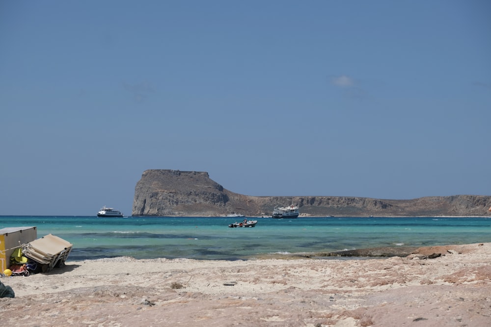 a beach with boats in the water and a mountain in the background