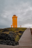 a wooden walkway leading to a yellow lighthouse