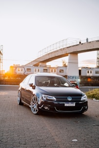 A sleek taxi car waiting in front of a busy train station at sunset.