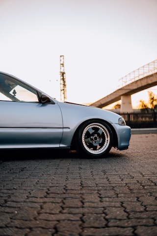 a car parked on a brick road next to a bridge
