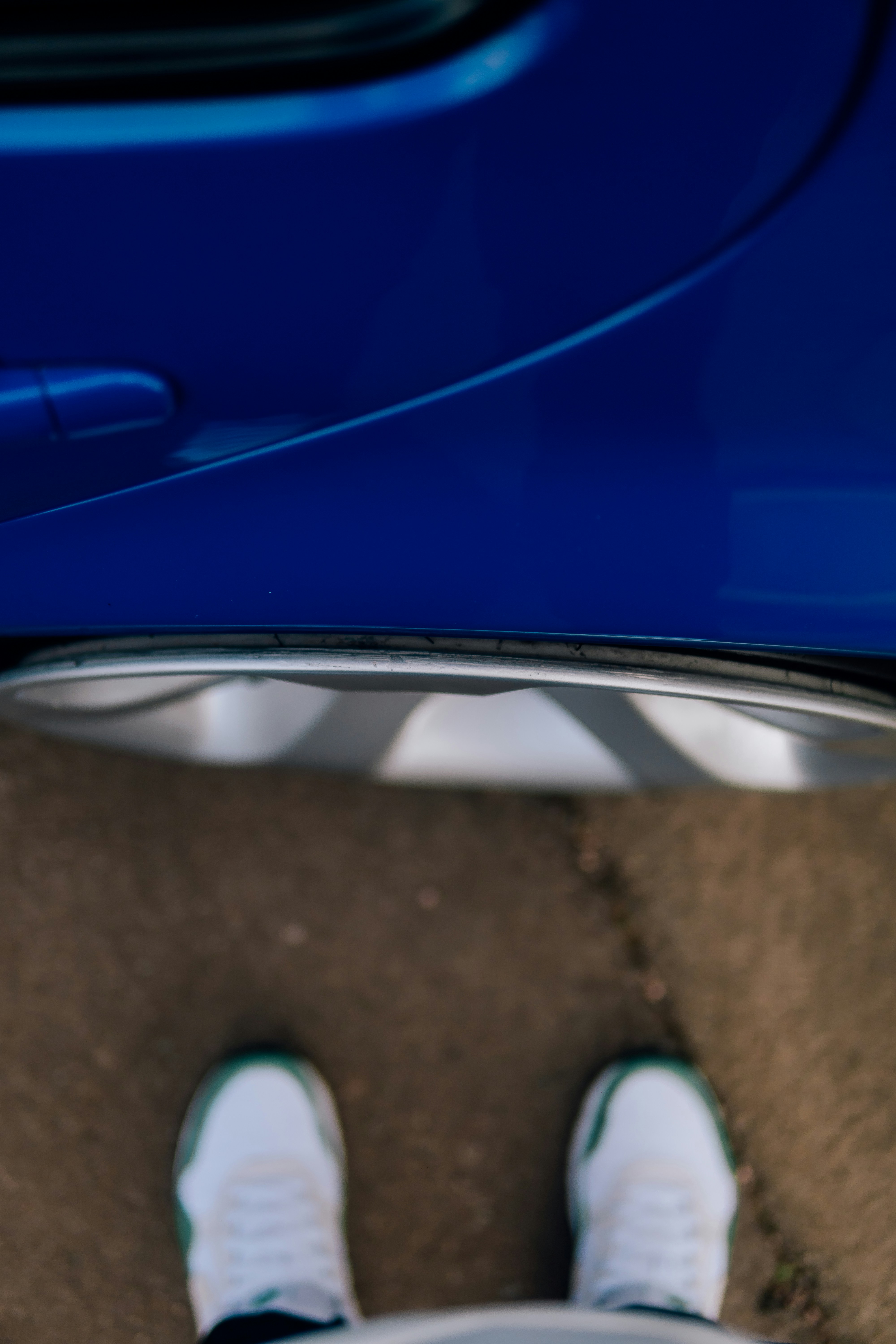 A person standing in front of a blue car