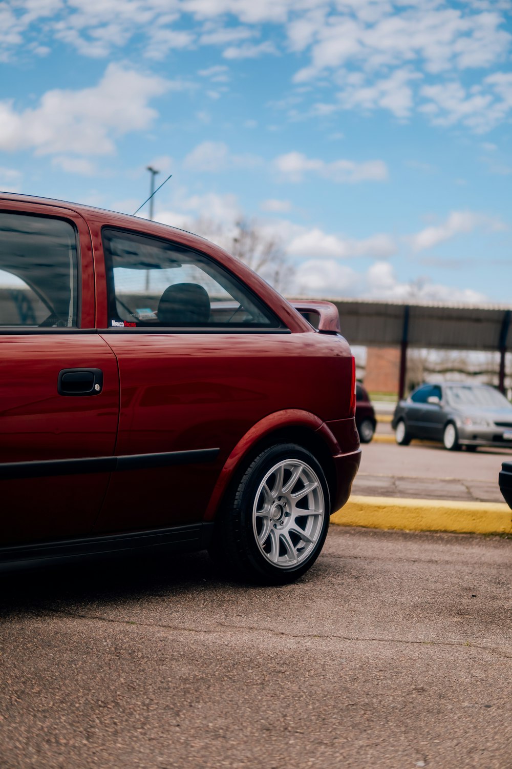 a red car parked in a parking lot next to a parking meter