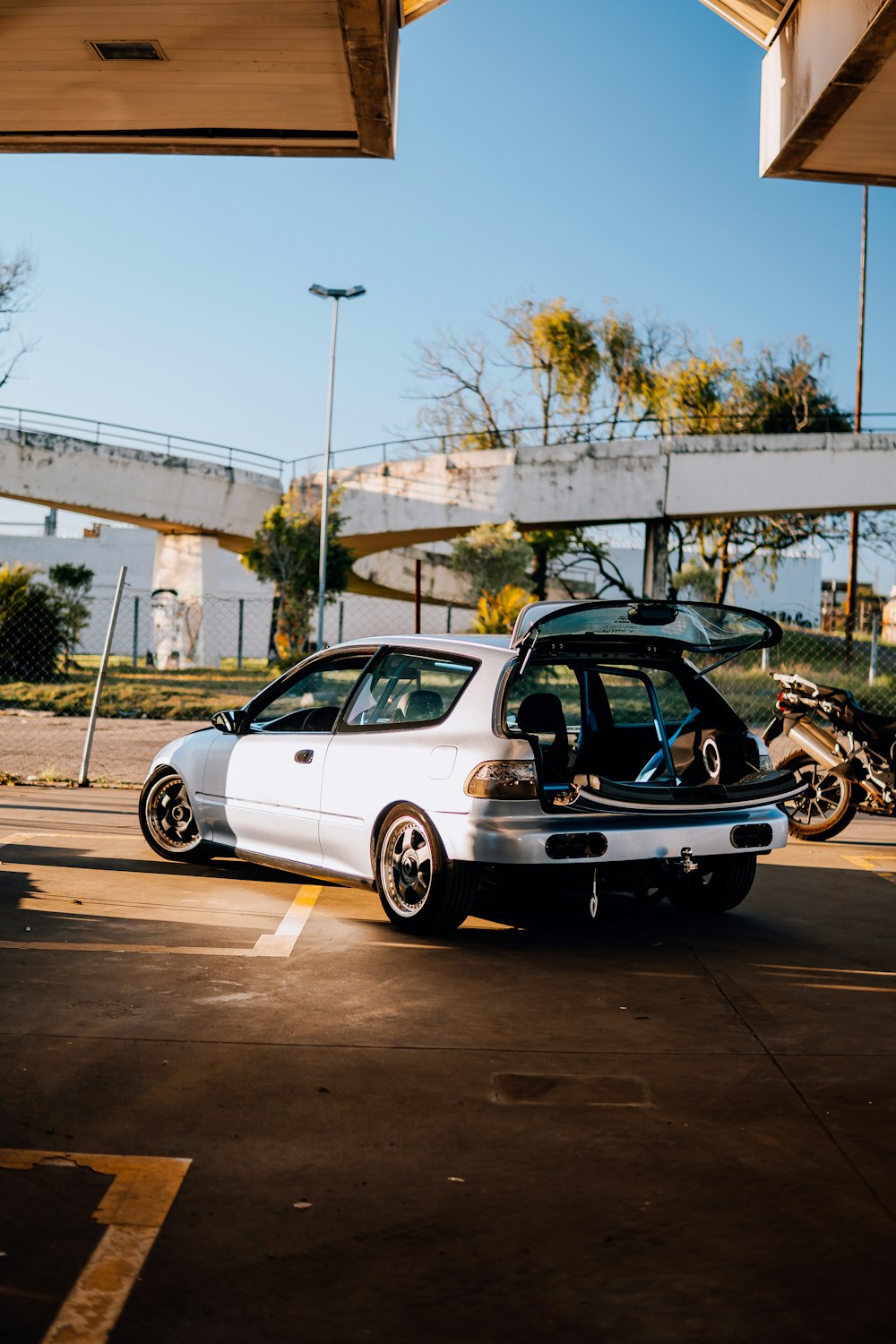 a white car parked in a parking lot next to a motorcycle