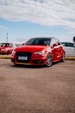 a red car parked in a parking lot next to other cars