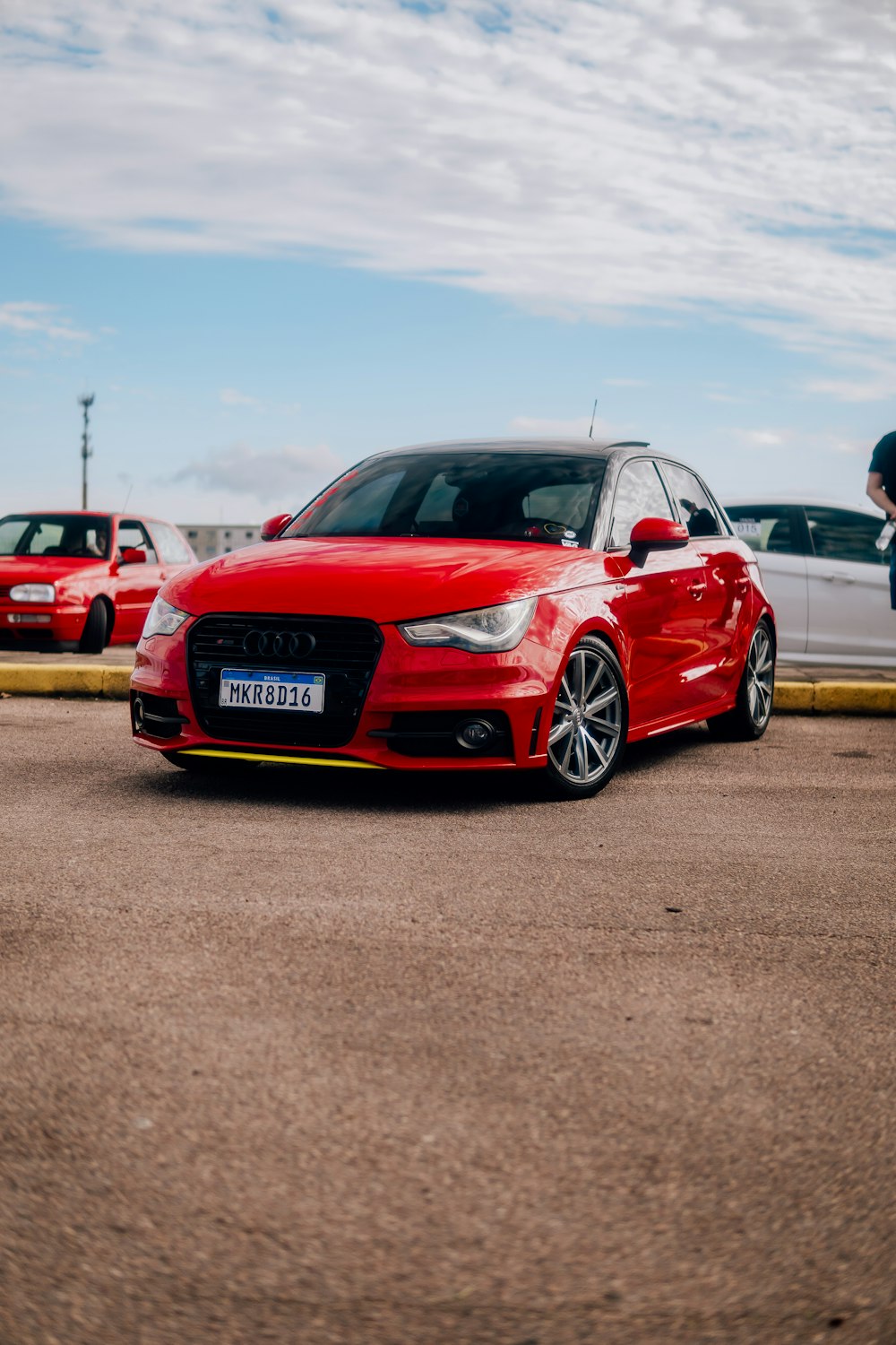 a red car parked in a parking lot next to other cars