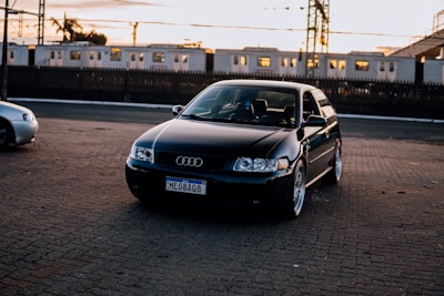 a black car parked in a parking lot next to a train