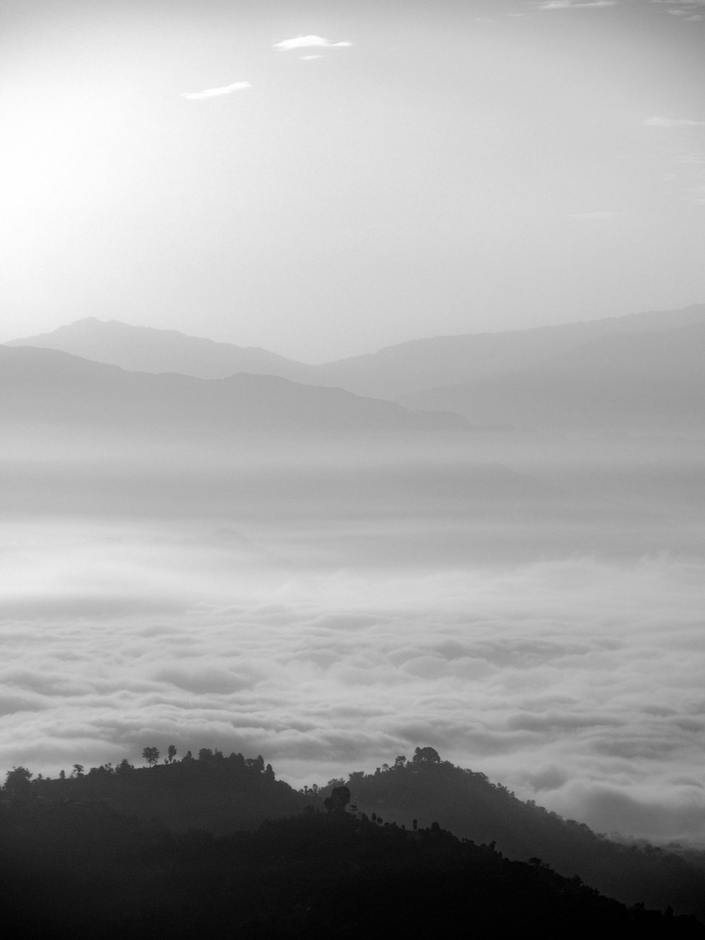 a black and white photo of a foggy mountain