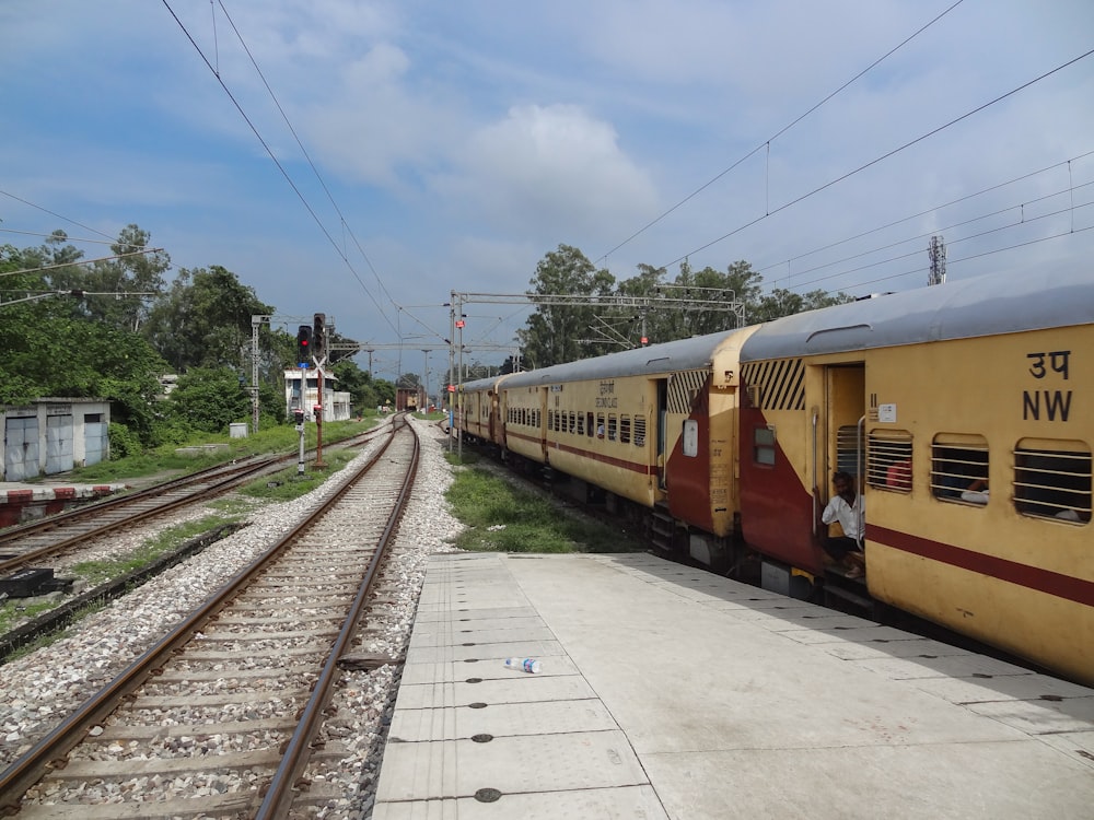 a yellow train traveling down train tracks next to a forest